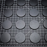 Array of 50mm round bases placed on a black background