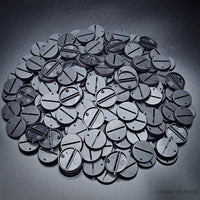 Macro shot of 32mm round slotted bases on a black surface.