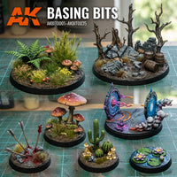 Individual painted miniature bases using AK Interactive Basing Bits on a cutting mat showing forest vegetation, dead tree with ruins and barrels, giant mushrooms with arrows, cacti with candles, sci-fi portal effects, and water lilies display bases