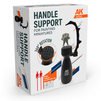 AK Interactive AK9565 Handle Support for Painting Miniatures retail box showing handle with 360 degree rotating base, arch finger rest, dwarf miniature mounted on pin, and included accessories callout for 2 holding pins and reusable adhesive paste
