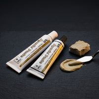 Aves Apoxie Paste 1 fl oz two-part adhesive with Part A and Part B tubes shown beside mixed paste on a palette knife for gap filling, bonding and repair work