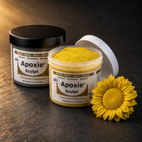 Aves Apoxie Sculpt 1lb Yellow — Part A tub open showing yellow putty, Part B tub behind, with a detailed sculpted sunflower head demonstrating fine petal detail
