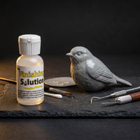 Aves Finishing Solution 30ml liquid finishing aid beside sculpting tools and an uncured bird model, used to smooth Apoxie Sculpt, reduce tool marks and clean tools