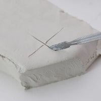 White DAS Modelling Clay block being cut with sculpting tool