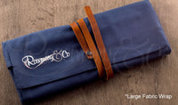 Rosemary & Co large fabric brush wrap shown closed on wooden surface with navy canvas body and leather strap