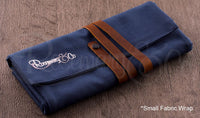 Rosemary & Co small fabric brush wrap shown closed on wooden surface with navy canvas body and leather strap