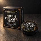 Brush Cleaner Soap box with gold-foil border beside the closed black screw-top tin