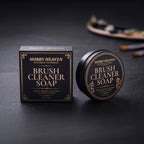 Brush Cleaner Soap presentation box and black tin on dark slate, paintbrushes and palette in the background