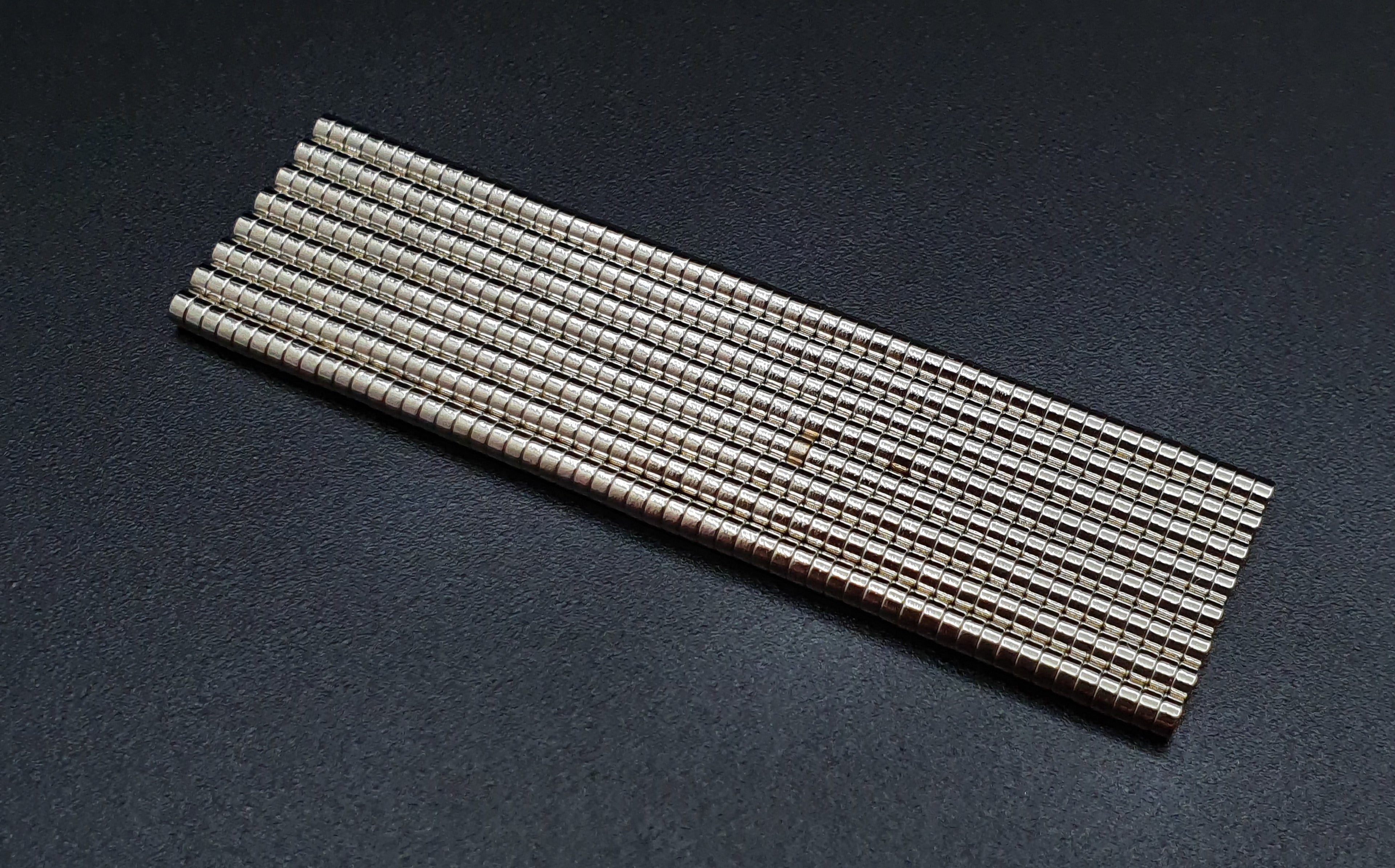 Rows of 2 x 1 mm neodymium disc magnets stacked into long columns on a dark background