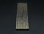 Stacked columns of 2 x 1 mm neodymium disc magnets standing upright on a dark background