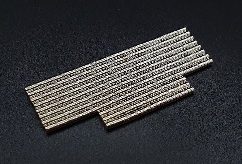 Two overlapping groups of stacked 2 x 1 mm neodymium disc magnets on a dark background