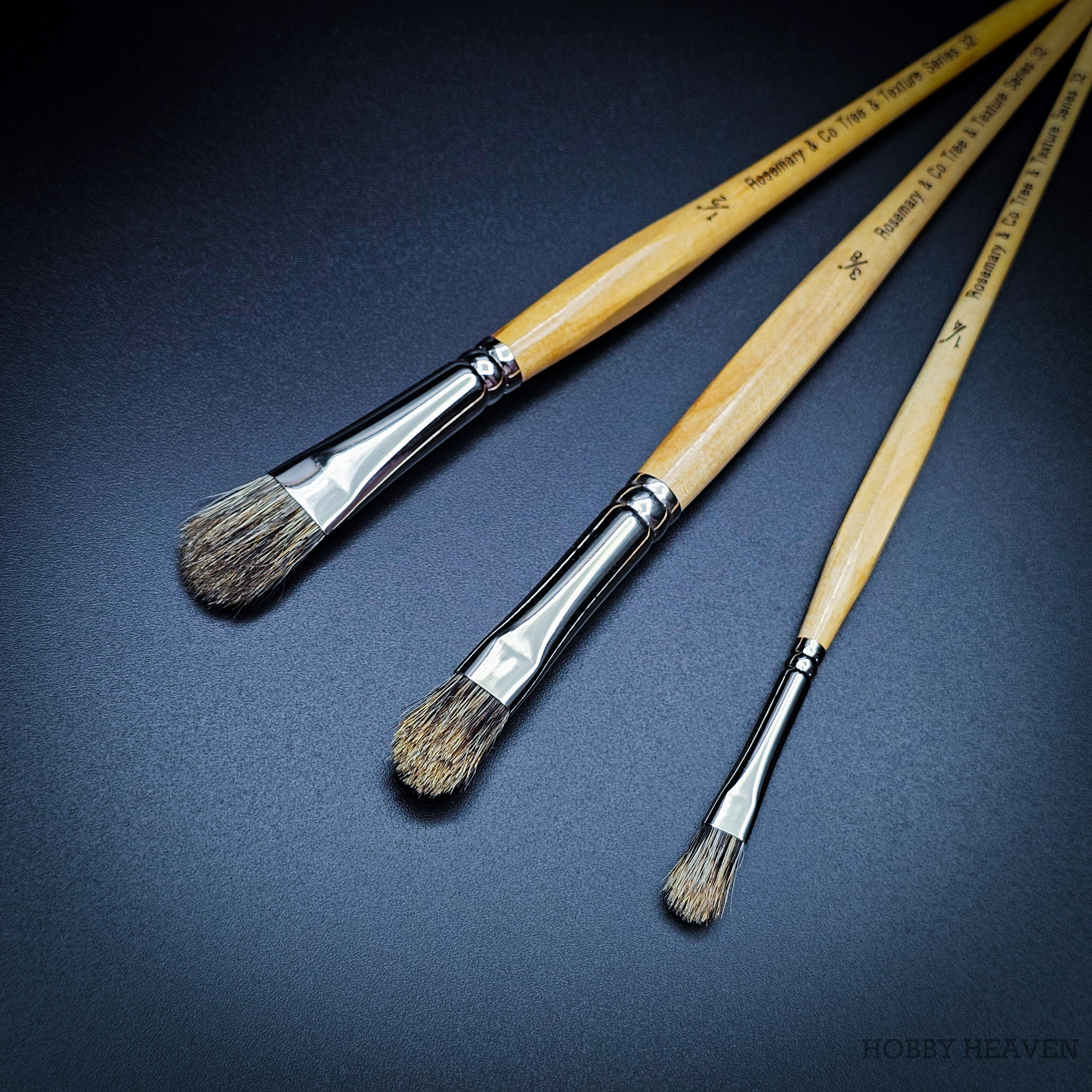 Three Rosemary & Co Series 32 badger tree & texture brushes fanned out, sizes 1/4, 3/8 and 1/2 inch, with light wood handles and stubby stippler heads