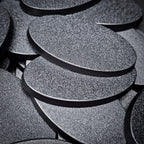 Close view of stacked 60x35mm oval plain bases, showing the textured top and the flat moulded rim