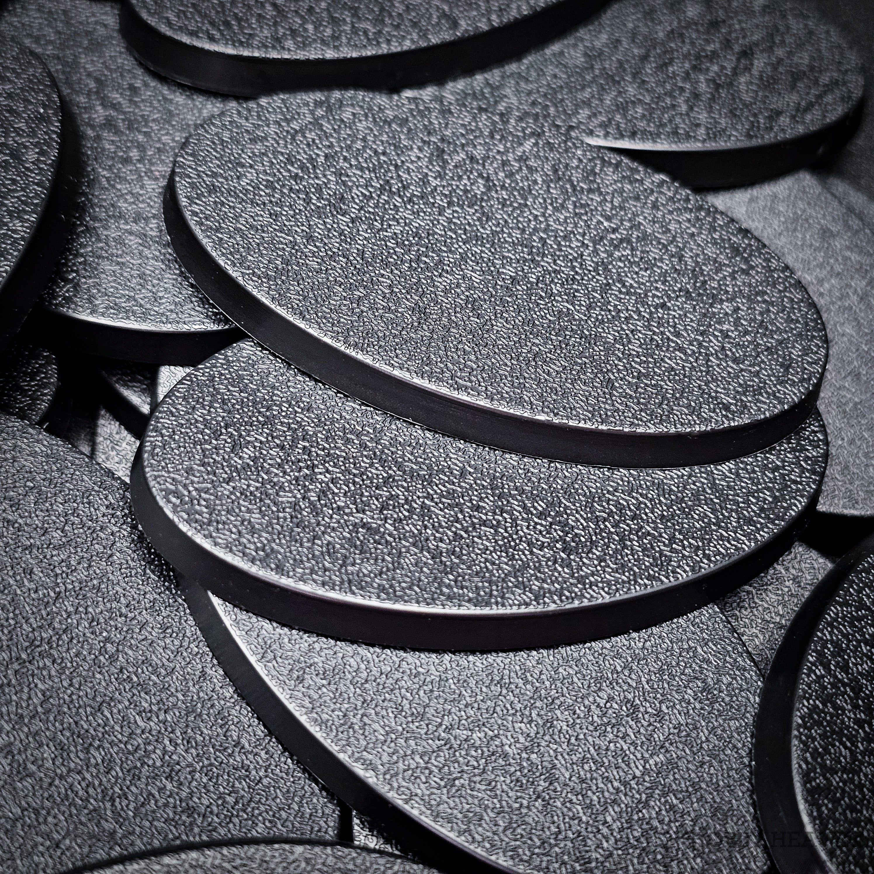 Close view of stacked 60x35mm oval plain bases, showing the textured top and the flat moulded rim