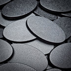 Overlapping 60x35mm oval plain plastic bases seen close up, their textured tops catching the light