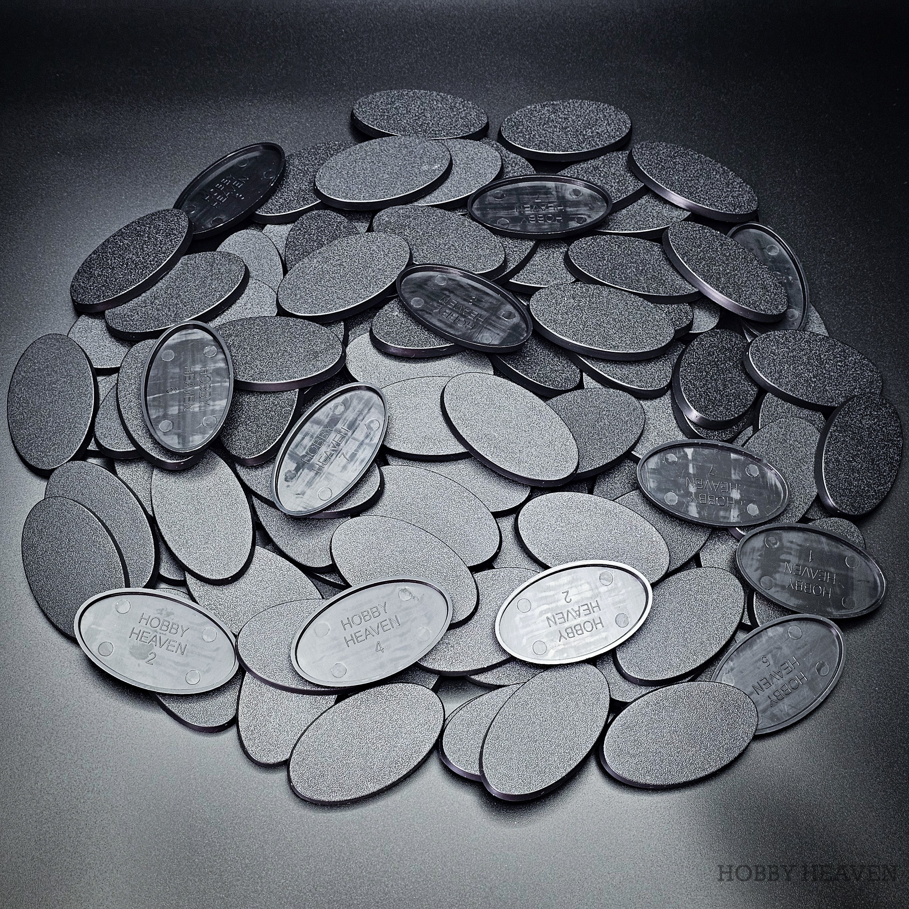 Cluster of 60x35mm oval plain plastic bases seen from above, edges and textured tops in close view