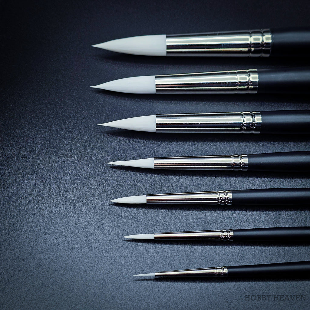 Close-up of nine Snowdrop brush heads in sizes 0 to 16 showing the tapered white taklon points and progressive size increase