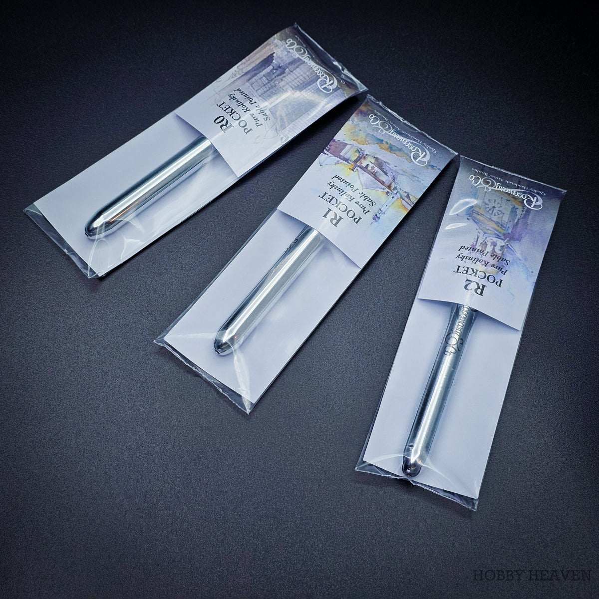 Three Pocket Kolinsky brushes in sealed packaging viewed from above showing the closed chrome handles