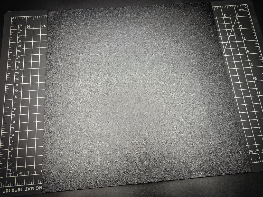Angled photograph of the 300mm square textured PETG base on a cutting mat with ruler markings visible for scale.