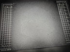 Angled photograph of the 300mm square textured PETG base on a cutting mat with ruler markings visible for scale.