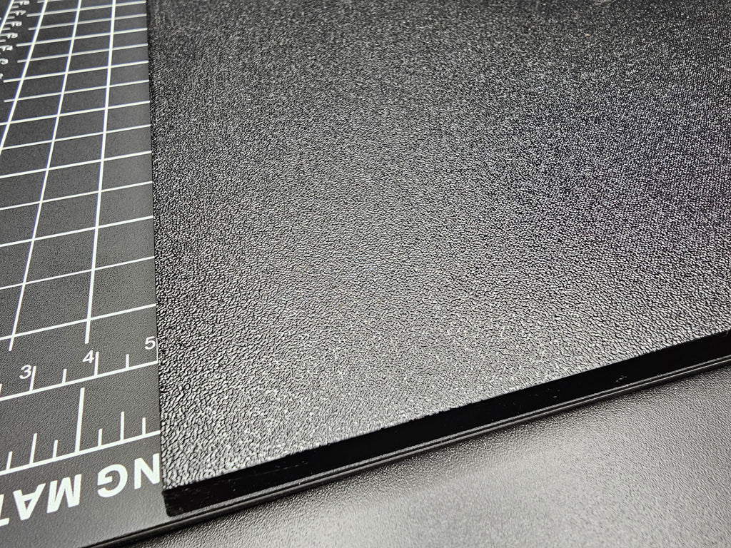 Close-up of the corner and edge of the 300mm square textured PETG base showing the textured surface detail and clean 6mm edge profile.