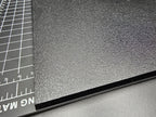 Close-up of the corner and edge of the 300mm square textured PETG base showing the textured surface detail and clean 6mm edge profile.