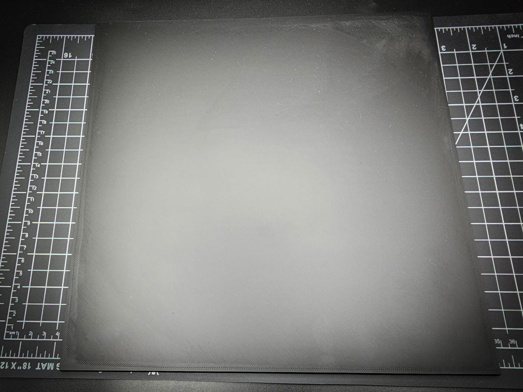 Top-down photograph of the 300mm square smooth PLA base on a cutting mat, showing the clean matte surface with subtle FDM layer lines.