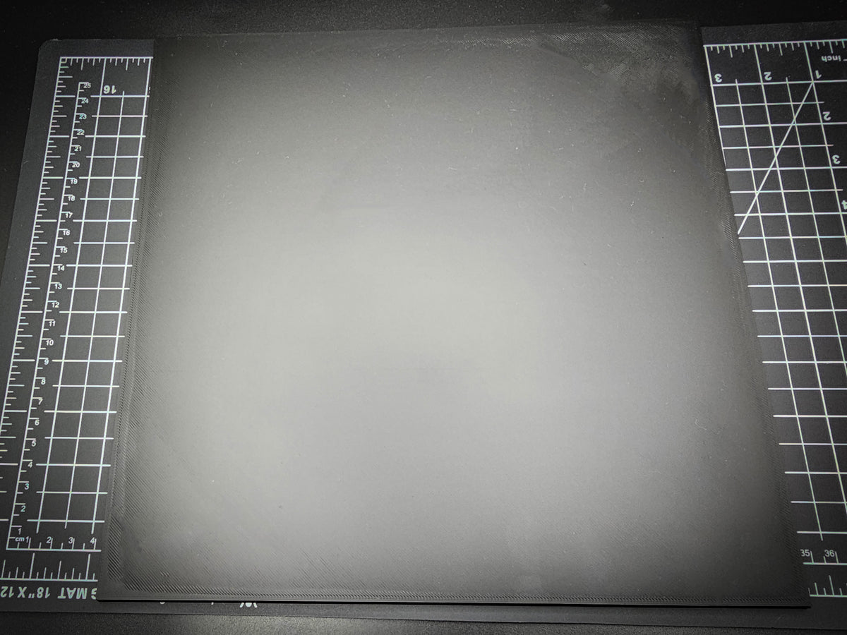 Top-down photograph of the 300mm square smooth PLA base on a cutting mat, showing the clean matte surface with subtle FDM layer lines.
