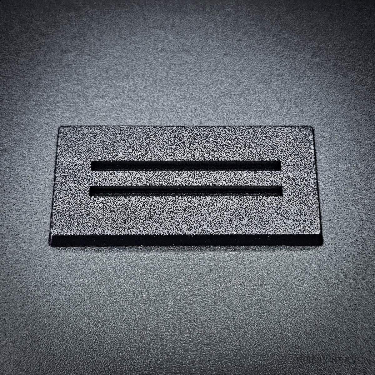 Single black 50x25mm rectangle slotted base, two parallel slots centred along the length