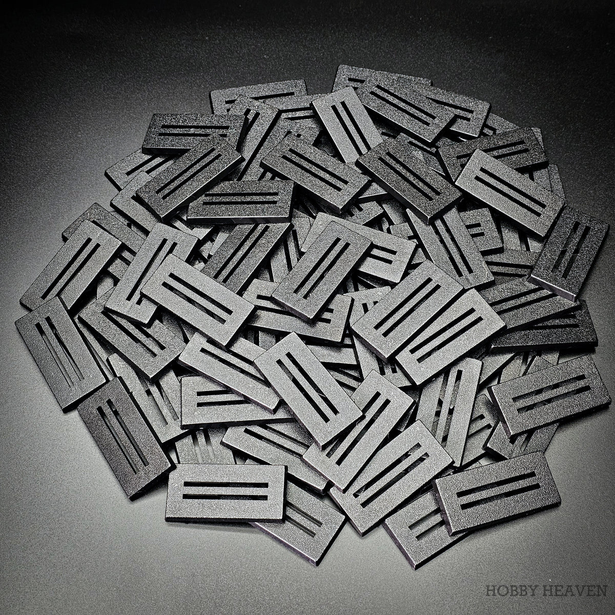 Pile of black 50x25mm rectangle slotted plastic bases, injection-moulded ABS