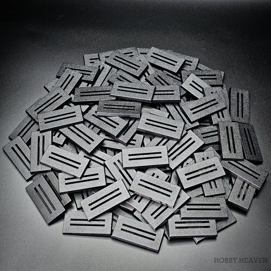 Large heap of black 50x25mm rectangle slotted bases on a grey background
