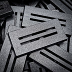 Angled close-up of a 50x25mm slotted base: bevelled edge, two parallel slots and textured top surface