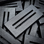 Close-up of black 50x25mm rectangle slotted bases showing the two parallel slots and fine textured top