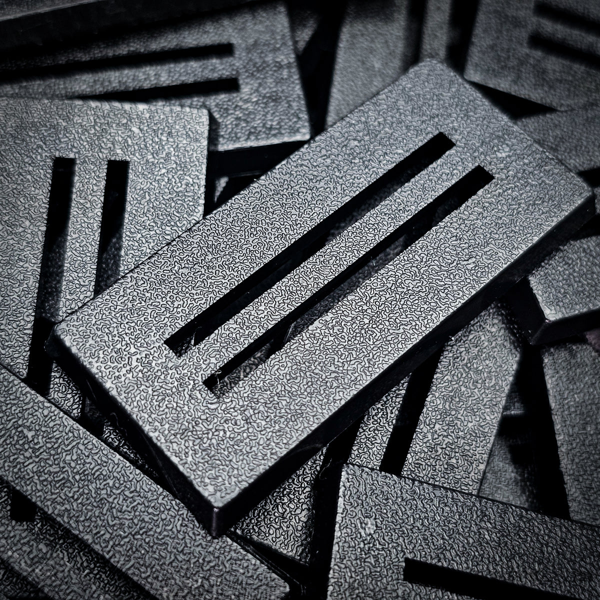 Close-up of black 50x25mm rectangle slotted bases showing the two parallel slots and fine textured top