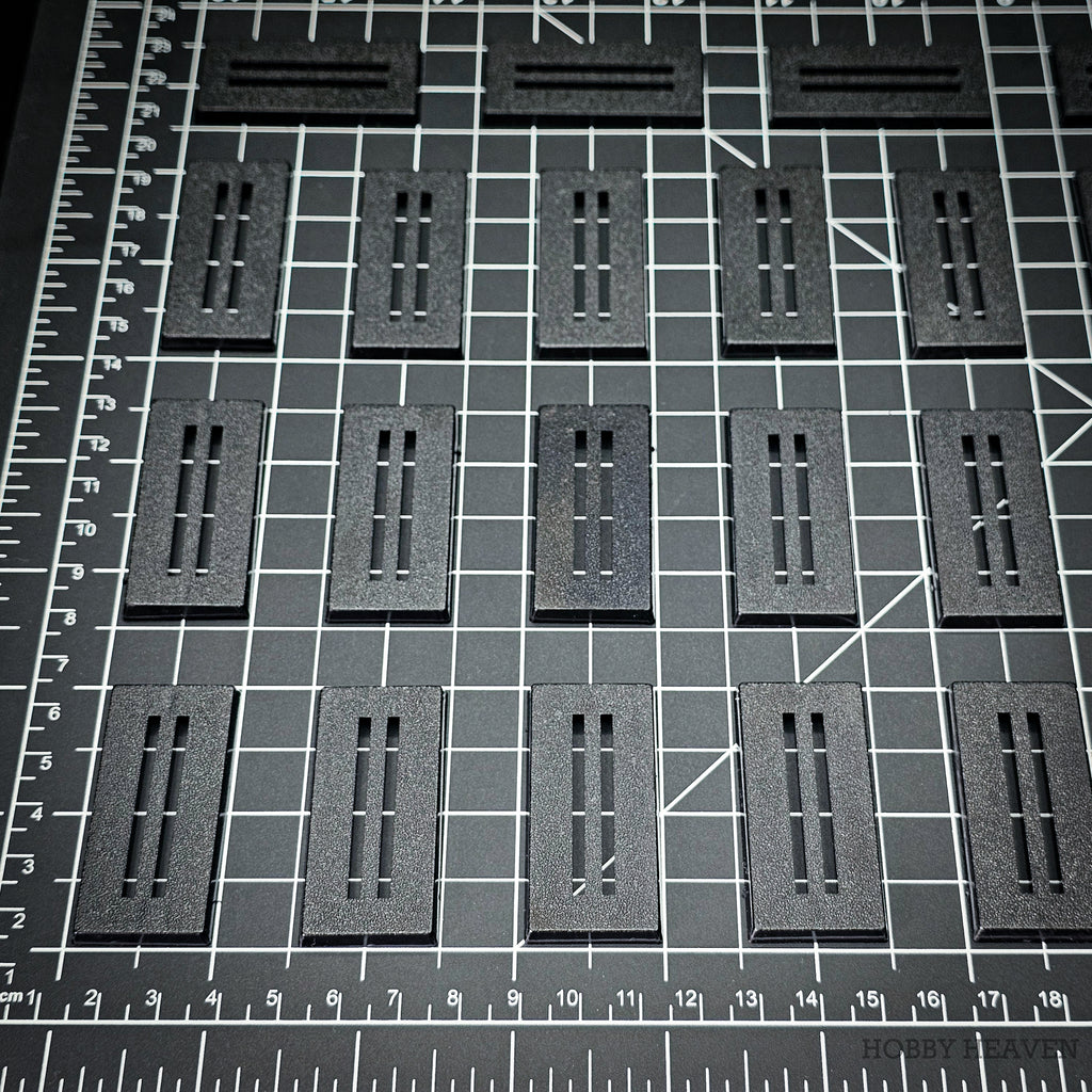 Rows of 50x25mm rectangle slotted bases on a centimetre cutting mat for scale