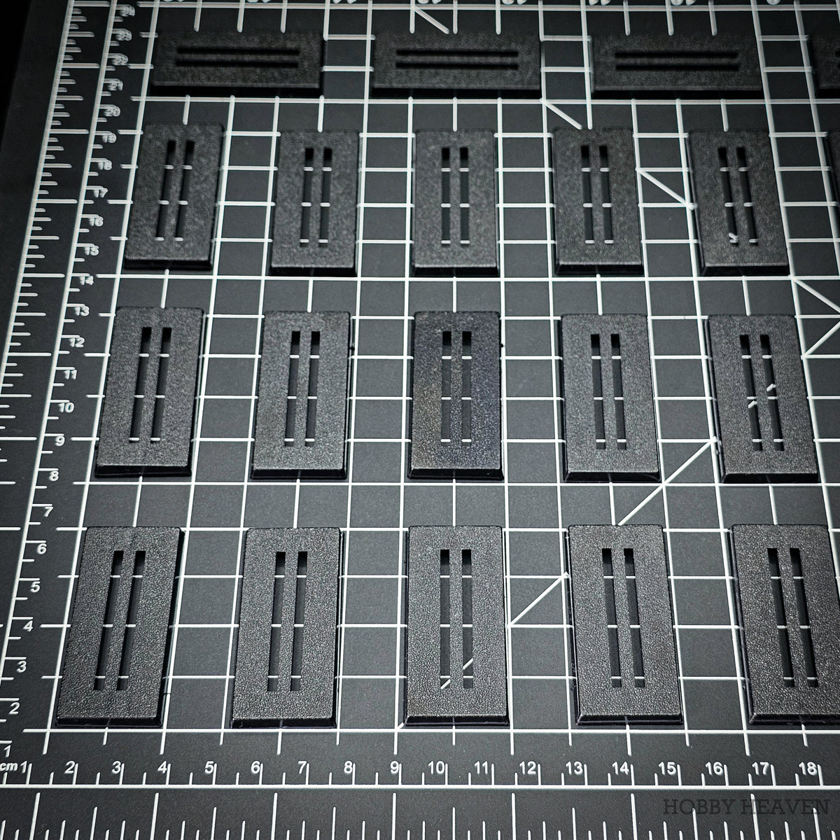 Rows of 50x25mm rectangle slotted bases on a centimetre cutting mat for scale