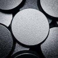 Detailed shot of a single 28mm round base, focusing on the quality of the material and the finish
