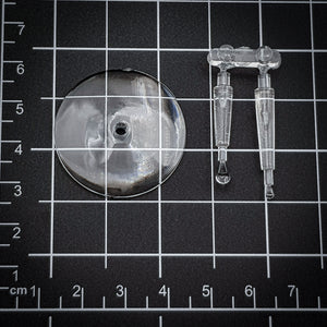 Clear acrylic 32mm flying base resting on a black modeler's cutting mat.