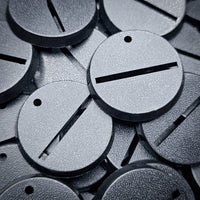 Close-up of 32mm round slotted bases amidst a pile of assorted bases
