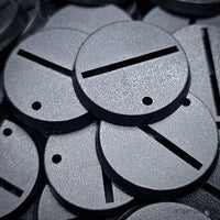 Detailed close-up view of 32mm slotted bases amidst a heap of assorted bases.
