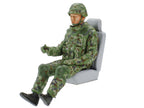The driver figure in camouflage and body armour, seated