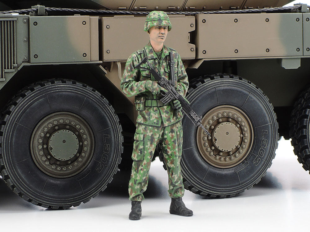 The full-body crew figure holding a rifle beside the wheels