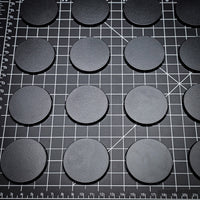 Array of 50mm round bases placed on a black background
