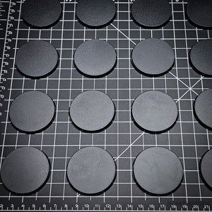 Array of 50mm round bases placed on a black background