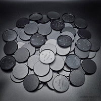 Collection of 50mm round bases lying together on a black background
