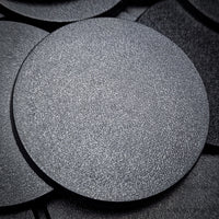 Close-up view of 60mm round bases with a black background, focusing on surface characteristics
