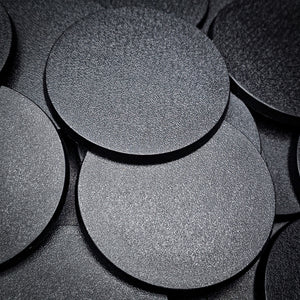 Detailed close-up of several 60mm round bases on a black backdrop, showcasing their finish"