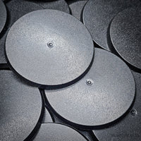 Close-up of 70mm round bases on a black surface
