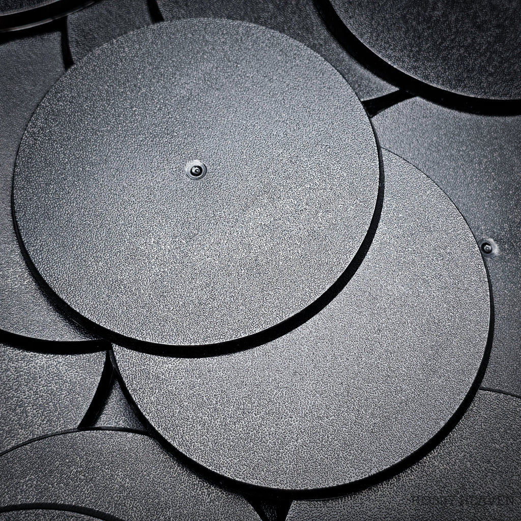 Cluster of 90mm round bases stacked on a black surface, close-up detail.