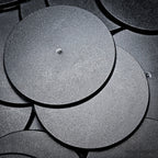 Cluster of 90mm round bases stacked on a black surface, close-up detail.